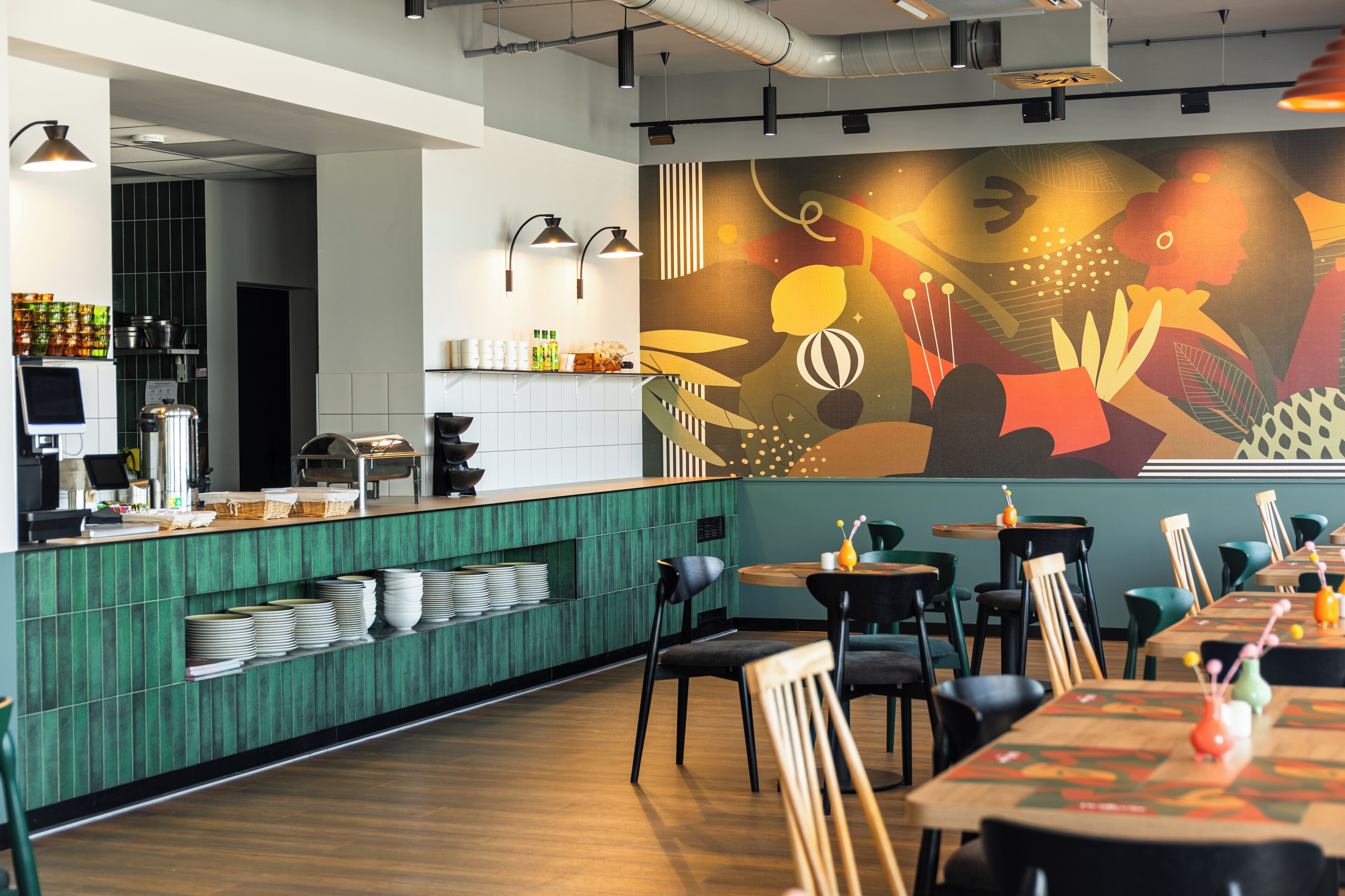 A restaurant interior with a green counter, white shelves, and a mural on the wall.