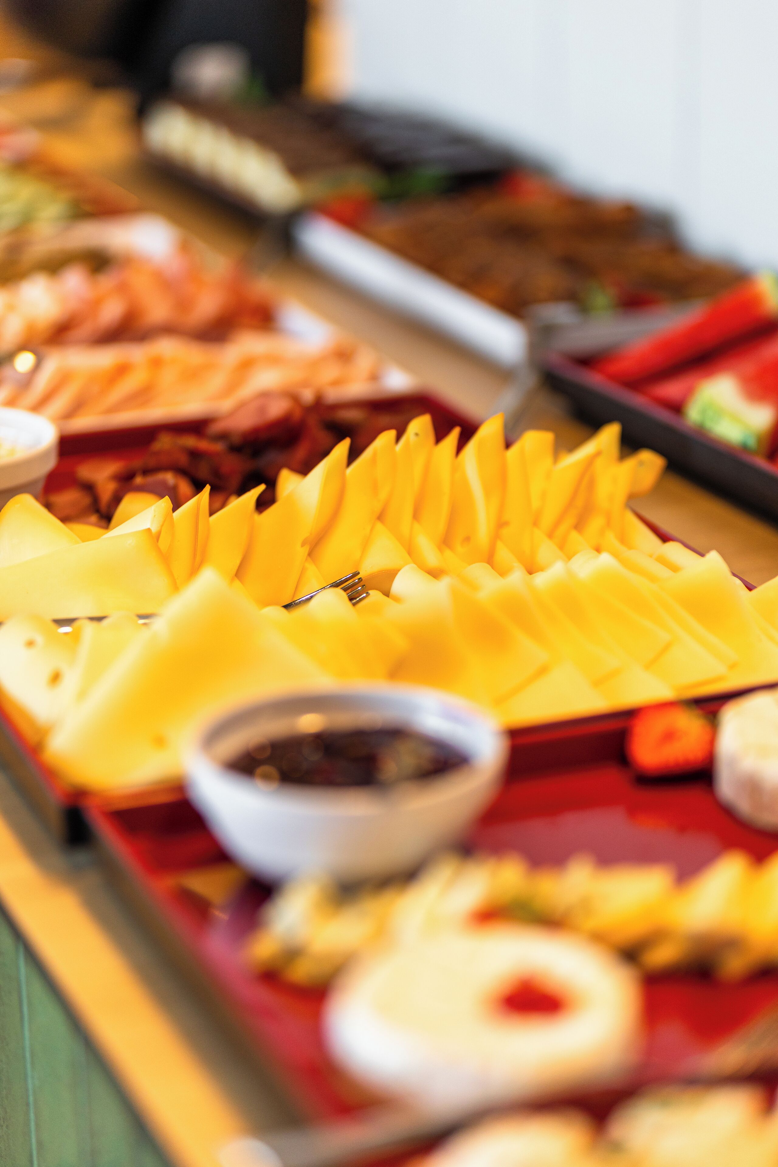 A buffet table with various food items including sliced fruits, vegetables, and a bowl of sauce.
