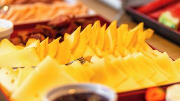 A buffet table with various food items including sliced fruits, vegetables, and a bowl of sauce.