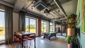 Un espace intérieur moderne comprenant une table de billard, des tabourets de bar et une piscine.