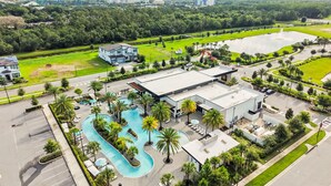 A resort with a swimming pool, a large building, and a parking lot.