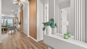 A modern hallway with wooden flooring, a white console table with decorative vases, and a contemporary light fixture.