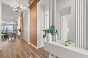 A modern hallway with wooden flooring, a white console table with decorative vases, and a contemporary light fixture.