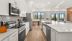 A modern kitchen with white cabinetry, stainless steel appliances, and a large island with a sink.