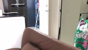 A brown sofa with two cushions in a room with a white floor and a door in the background.