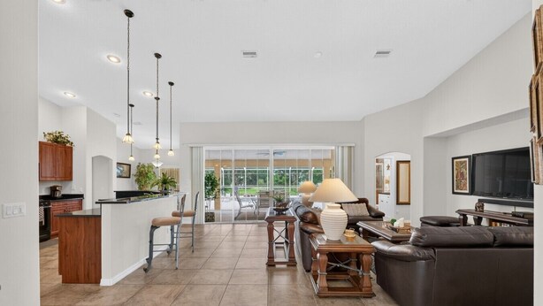 A spacious living area with a large sofa, a dining table, and a kitchen area with wooden cabinets and a bar. - Villa Corthouts: Luxury home close to bike trail! (Inverness)