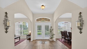 A spacious entryway with a tiled floor, a potted plant, and a dining area with chairs. - Villa Corthouts: Luxury home close to bike trail! (Inverness)