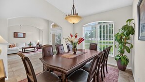 A dining area with a large table, chairs, and a hanging light fixture. - Villa Corthouts: Luxury home close to bike trail! (Inverness)