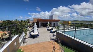 Uma área de piscina no terraço, com mobiliário externo e vista para a paisagem.
