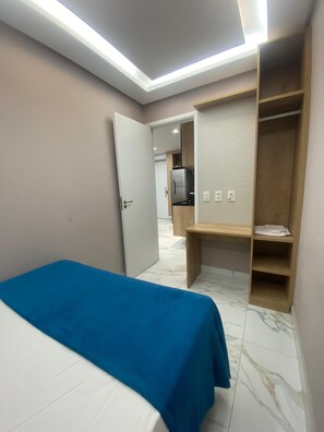 A hotel room with two beds, a wooden wardrobe, a small desk, and a kitchenette in the background. - Porto Atlantis Vista Mar 308 by La Playa (Ipojuca)