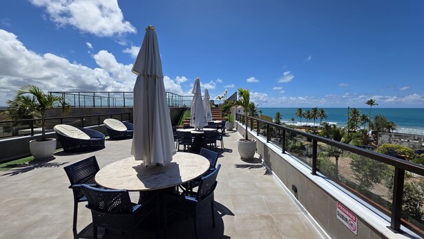 A rooftop terrace with outdoor seating, a view of the ocean, and a 'Prohibido Subir' sign. - Porto Atlantis Vista Mar 308 by La Playa (Ipojuca)