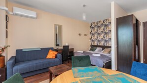 Een knus ingerichte kamer met een slaapbank, een klein tafeltje, een bed en een kledingkast.