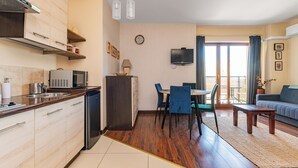 Een ruimtelijke leefruimte met een kitchenette, eethoek en een slaapbank.