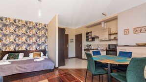 Een compacte kamer met een bed, een klein houten tafeltje en een zithoek met stoelen.