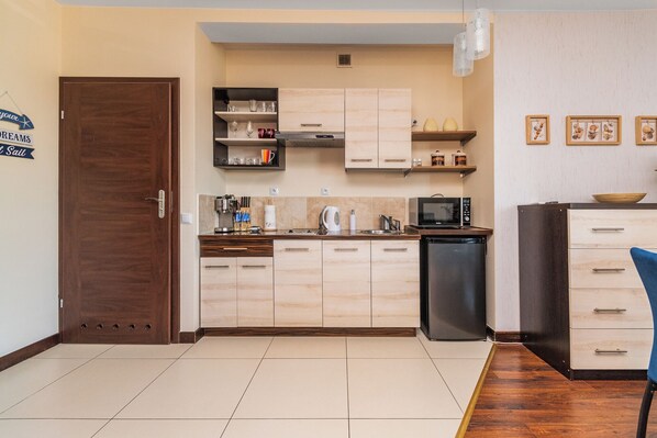 Una cocina compacta con armarios de madera, microondas y un refrigerador pequeño.
