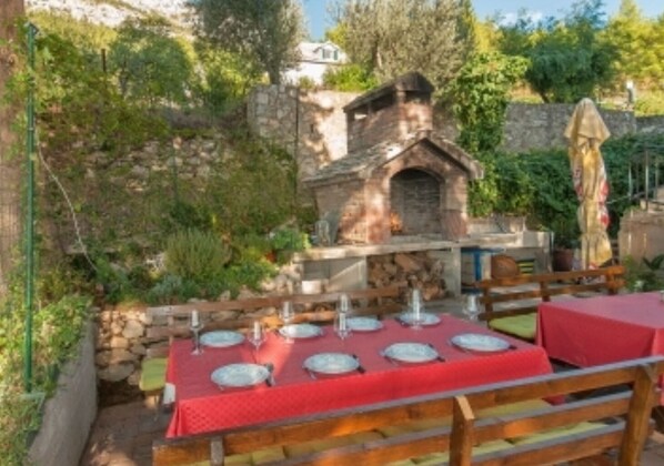 Enjoy a traditional dining experience in a secluded outdoor setting surrounded by lush greenery and a stone building.