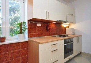 Enjoy cooking in this well-equipped kitchen with a stove, oven, and sink, offering a view of the surrounding greenery.
