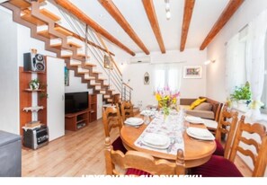 Cozy living area with a high ceiling, wooden staircase, and dining table for a meal.