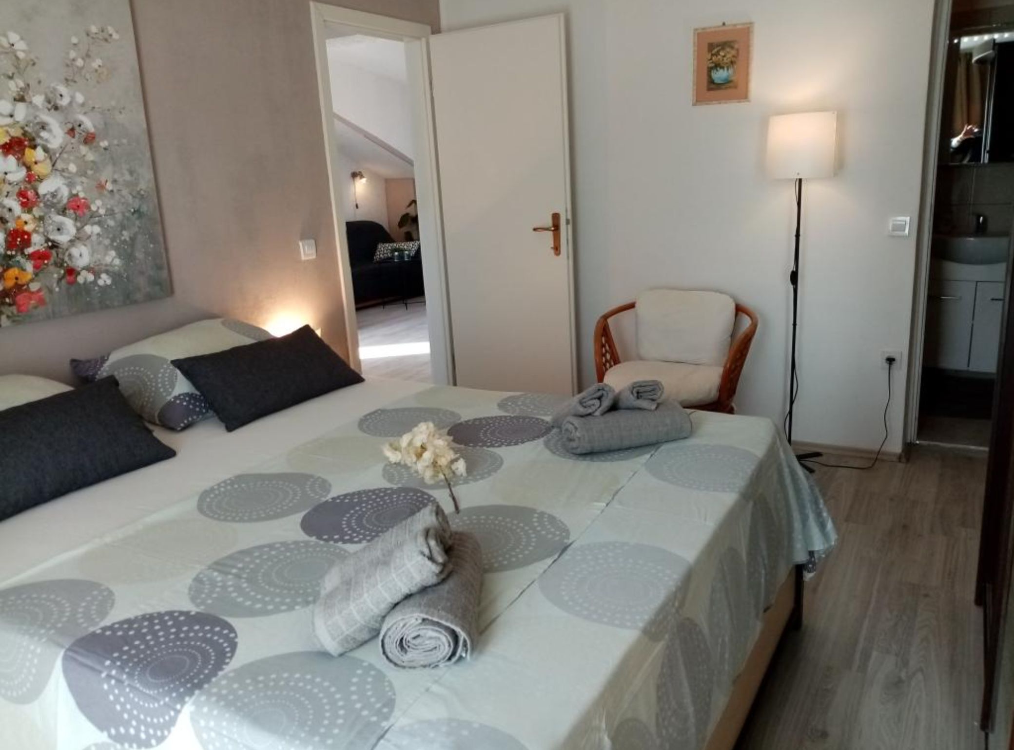 A hotel room with a bed, a chair, a lamp, and a painting on the wall.