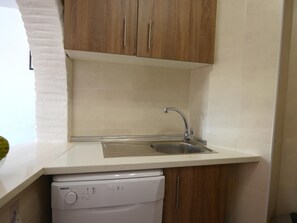 A compact kitchen with a dishwasher, a sink, and wooden cabinets.