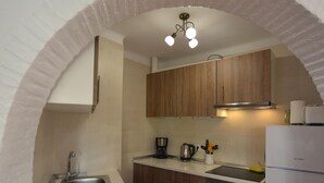 Una cocina con lavamanos, estufa y alacenas bajo un techo abovedado.