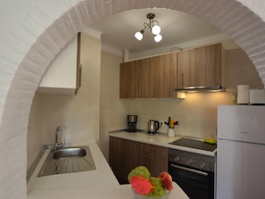 Una cocina con lavamanos, estufa y alacenas bajo un techo abovedado.