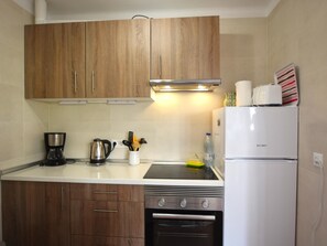 A kitchen with wooden cabinets, a white refrigerator, a stove, a coffee maker, and a kettle. - Central apartment with large terrace near Torrecilla (Nerja)