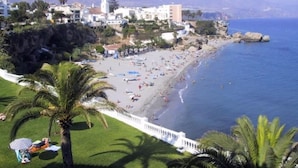 Un pueblo costero con playa, edificios y una montaña al fondo.