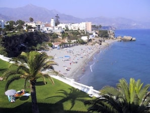 Un pueblo costero con playa, edificios y una montaña al fondo.