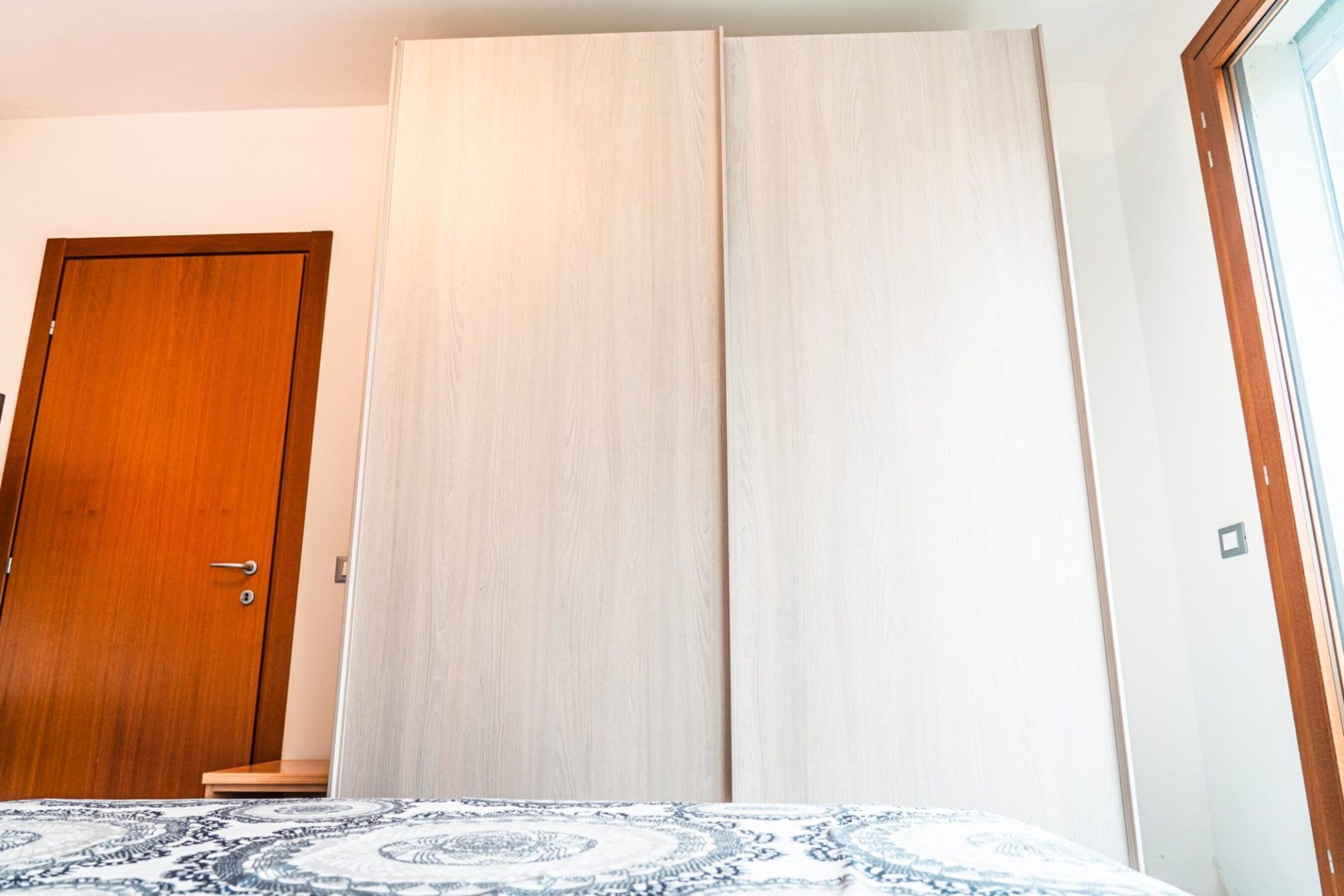 Un dormitorio con cama, una puerta de madera y un armario.