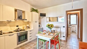 Una cocina moderna con armarios blancos, una estufa y un comedor con una mesa para dos.