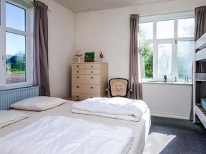 A bedroom with two beds, a dresser, a chair, and a window with curtains. - 4 Person Holiday Home in Skaerbaek (Skaerbaek)