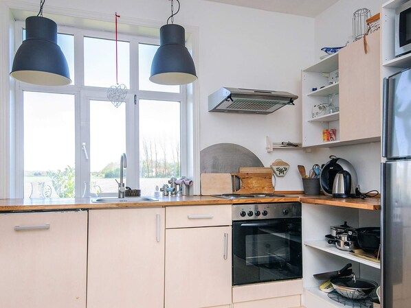 A kitchen with a double sink, a stove, and a refrigerator.