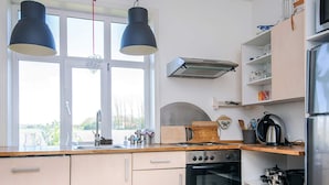 A kitchen with a window, two pendant lights, a stove, oven, and various kitchen utensils. - 4 Person Holiday Home in Skaerbaek (Skaerbaek)