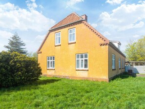 A two-story house with a sloped roof, a chimney, and a well-maintained lawn. - 4 Person Holiday Home in Skaerbaek (Skaerbaek)
