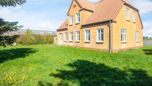 A two-story house with a red-tiled roof and a grassy yard. - 4 Person Holiday Home in Skaerbaek (Skaerbaek)