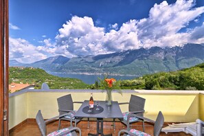 Eine Terrasse mit Tisch für zwei Personen, mit Blick auf eine Berglandschaft und einen See.
