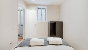 Une chambre à coucher avec un lit, deux serviettes, une armoire et une fenêtre.