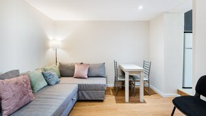 Un petit salon moderne comprenant un canapé, une table à manger et une chaise.