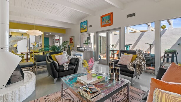 A spacious living area with a modern design, featuring a fireplace, comfortable seating, and large windows offering views of the outdoors.