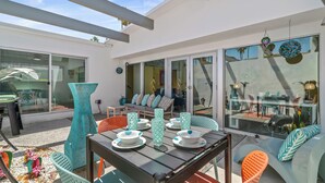An outdoor dining area with a table set for four, surrounded by colorful chairs and a large decorative vase.