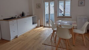 A modern kitchen with white cabinetry, a wooden countertop, and a dining area with a table and chairs.