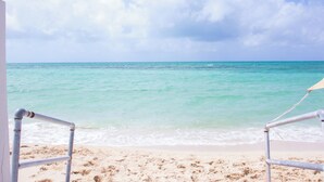 A beach with clear turquoise water and a cloudy sky. - Tangerine Sunsets Pomelo East (Nassau Bahamas)