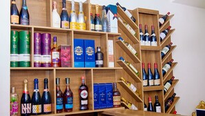A wine rack with various bottles and boxes of liquor. - Borelie Guest House  (Douala)