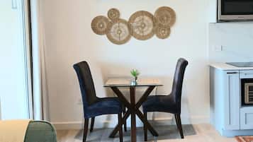 A dining area with a table and chairs, a wall-mounted air conditioner, and a kitchen area with a microwave.