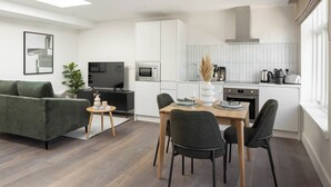 A modern living room with a sofa, TV, and dining area with chairs and a table. - Urban Rest Dublin Central (Dublin)