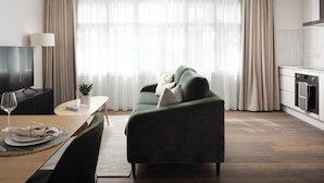 A modern living room with a sofa, a dining table set for two, a TV, and a kitchen area visible through the window. - Urban Rest Dublin Central (Dublin)