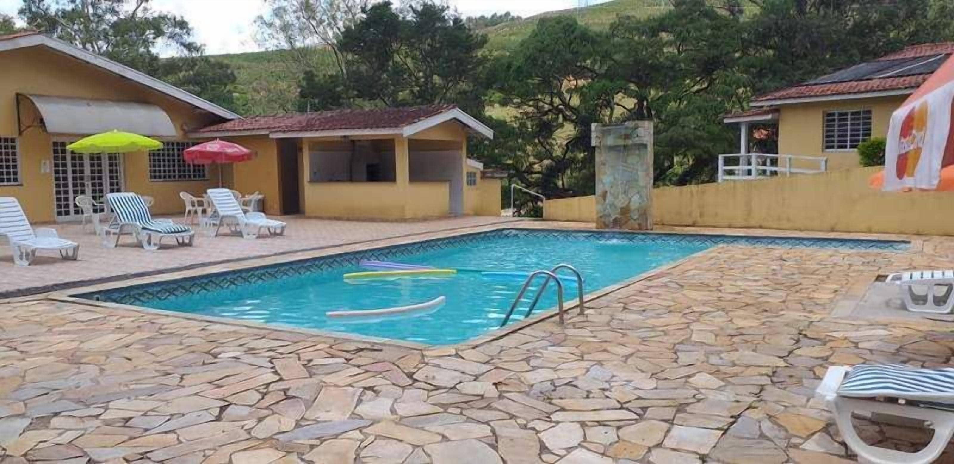 Une piscine avec des carreaux de pierre, des chaises longues et des parasols.