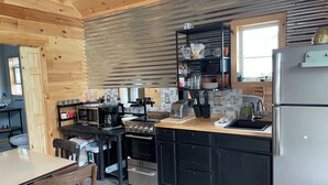 A modern kitchen with a wooden ceiling, black cabinetry, stainless steel appliances, and a window providing natural light. - Quiet 2-bedroom country cabin with scenic views 3 miles from Norwich NY. (Norwich)