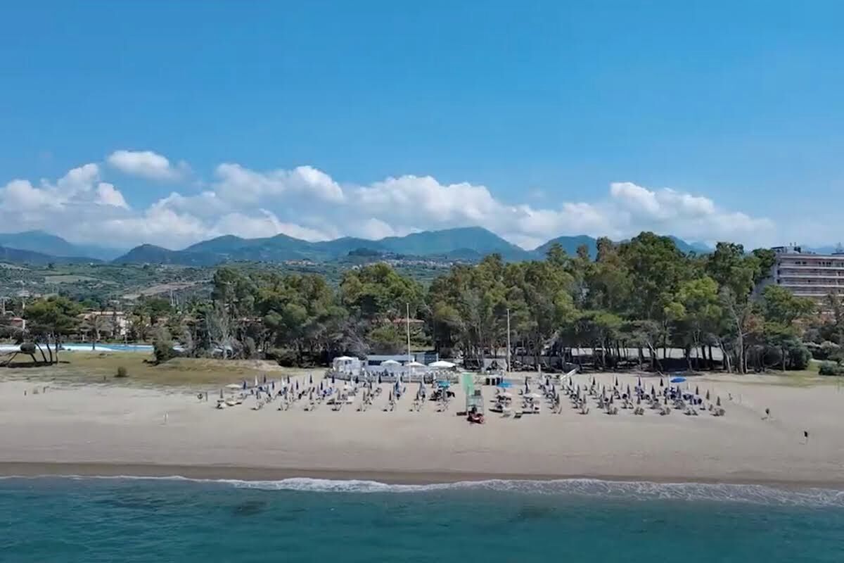 A beach with a clear view of the sea and distant mountains.